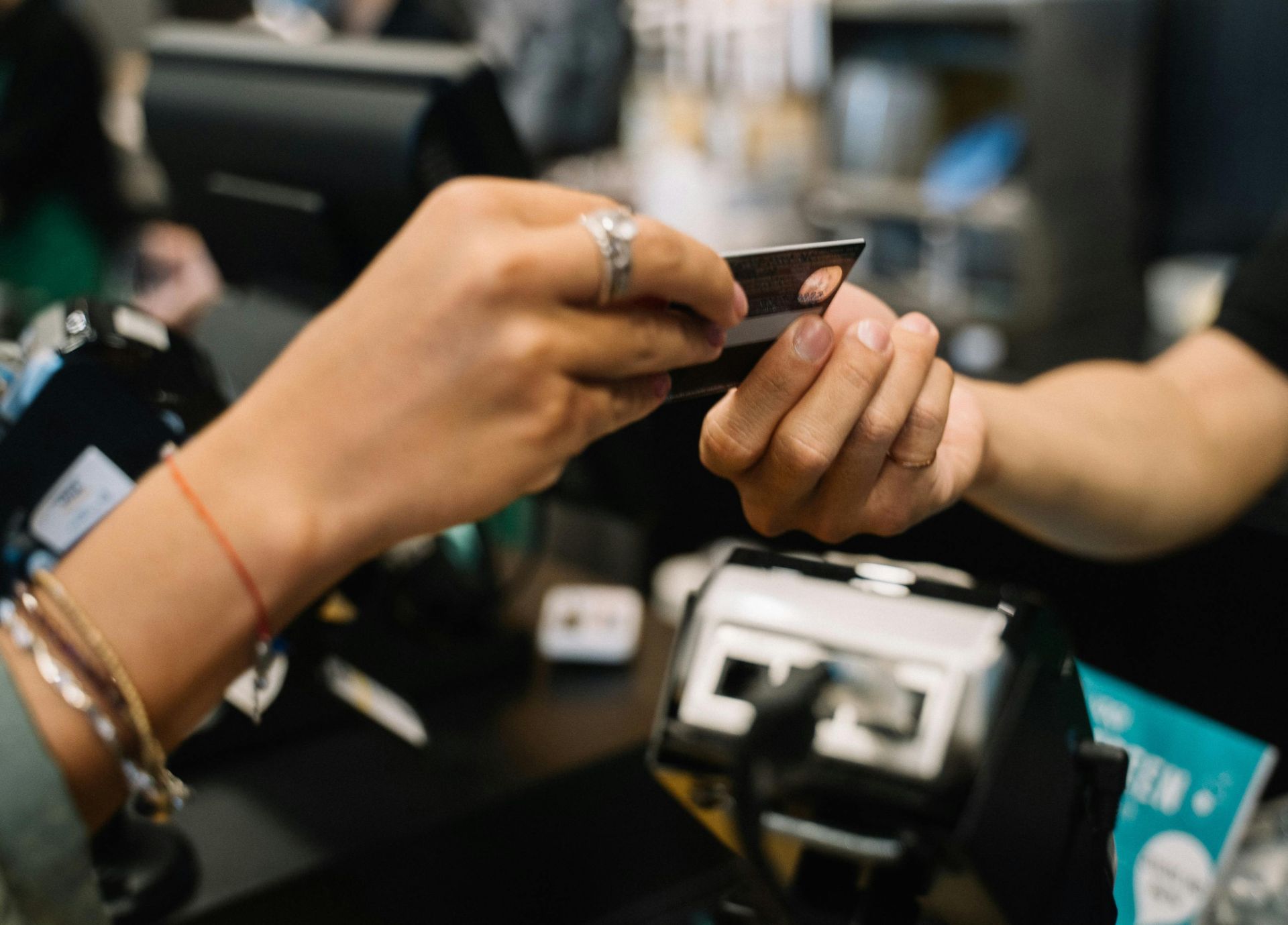 Close-up of hands completing a payment transaction at a retail checkout using a bank card.
